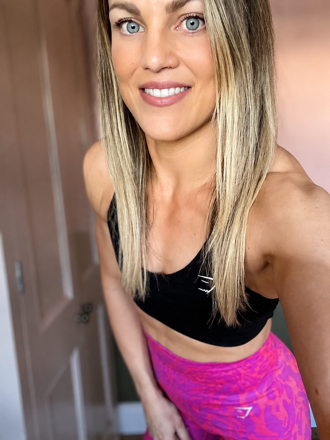 Emma Brooks smiling at the camera in a black crop top and pink leggings
